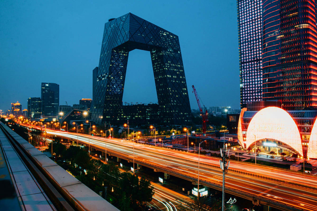 Modern Beijing cityscape at dusk featuring CCTV Headquarters with illuminated highway and red office building