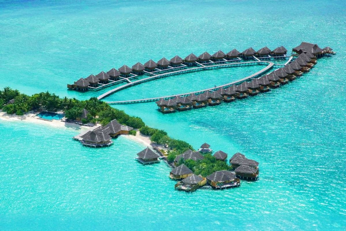 Aerial view of Taj Exotica Resort and Spa with overwater bungalows connected by wooden boardwalks in crystal clear turquoise 
