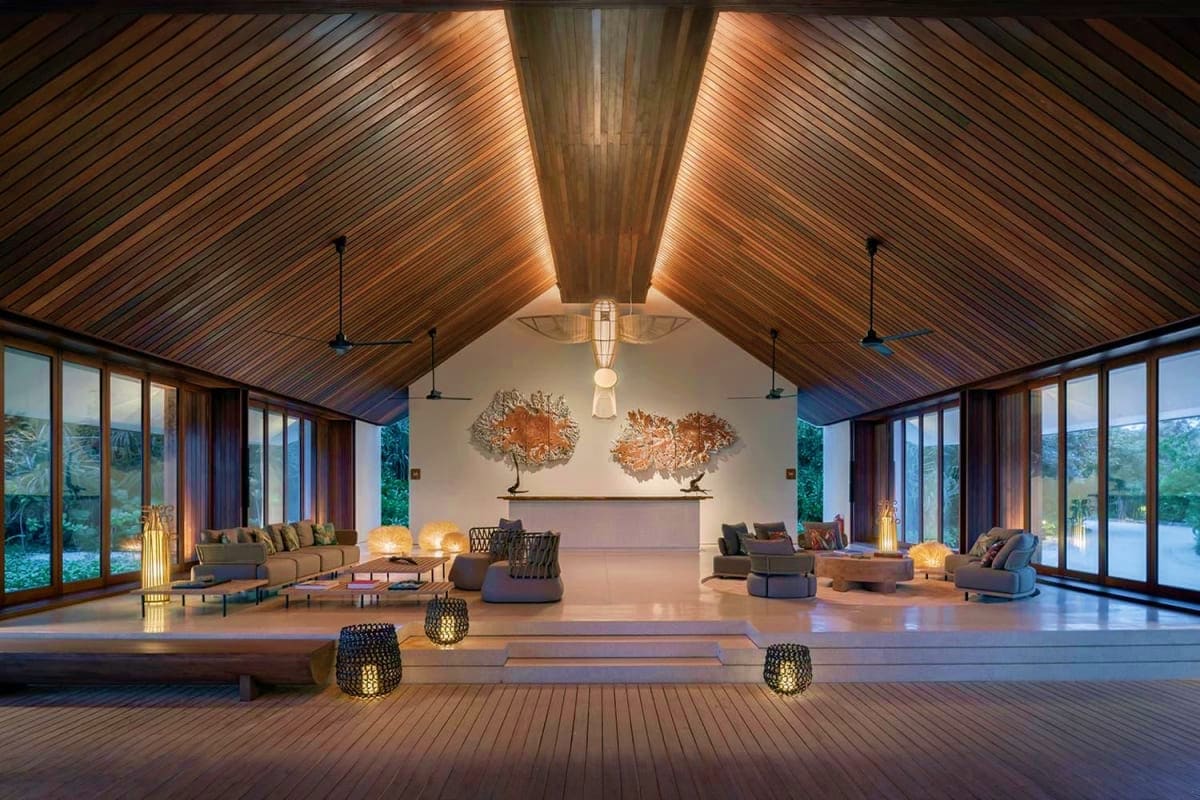 Modern luxury wellness resort interior with wooden vaulted ceiling, floor-to-ceiling windows, lounge seating, decorative copp