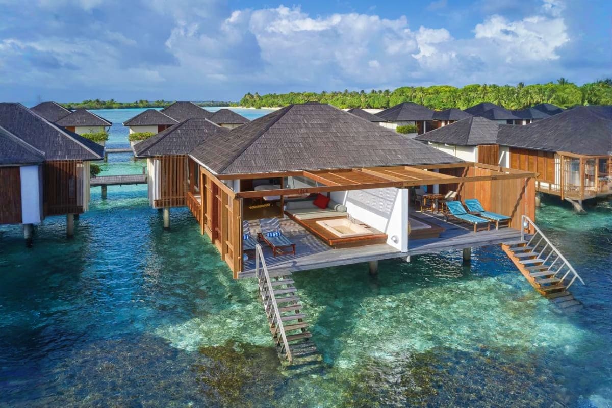 Luxury overwater bungalows with dark roofs at Medhufushi Island Resort in the Maldives, featuring wooden decks, turquoise lag