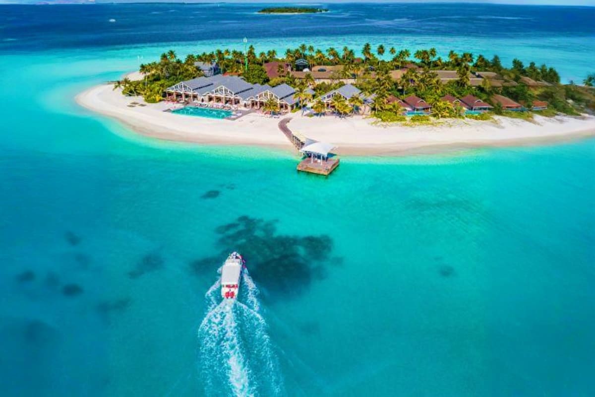 Aerial view of JW Marriott Maldives Resort with speedboat approaching white sand beach, turquoise lagoon, and overwater bunga