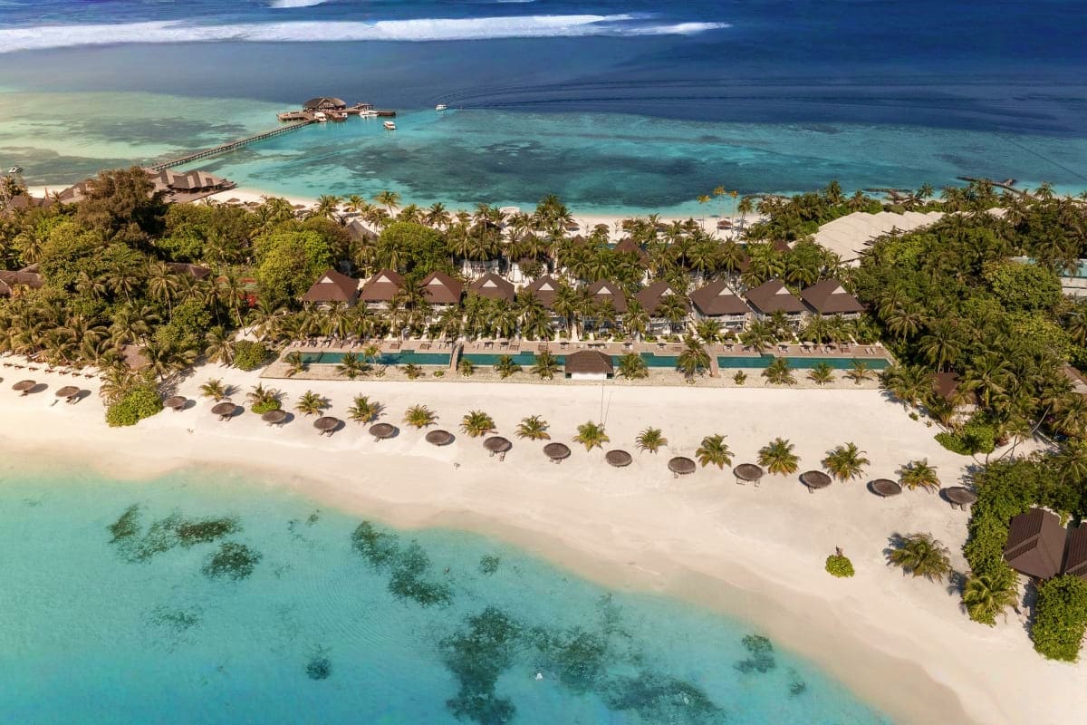 Aerial view of Sun Siyam Olhuveli Resort showing beach bungalows, white sand, turquoise lagoon, and overwater pier in the Mal
