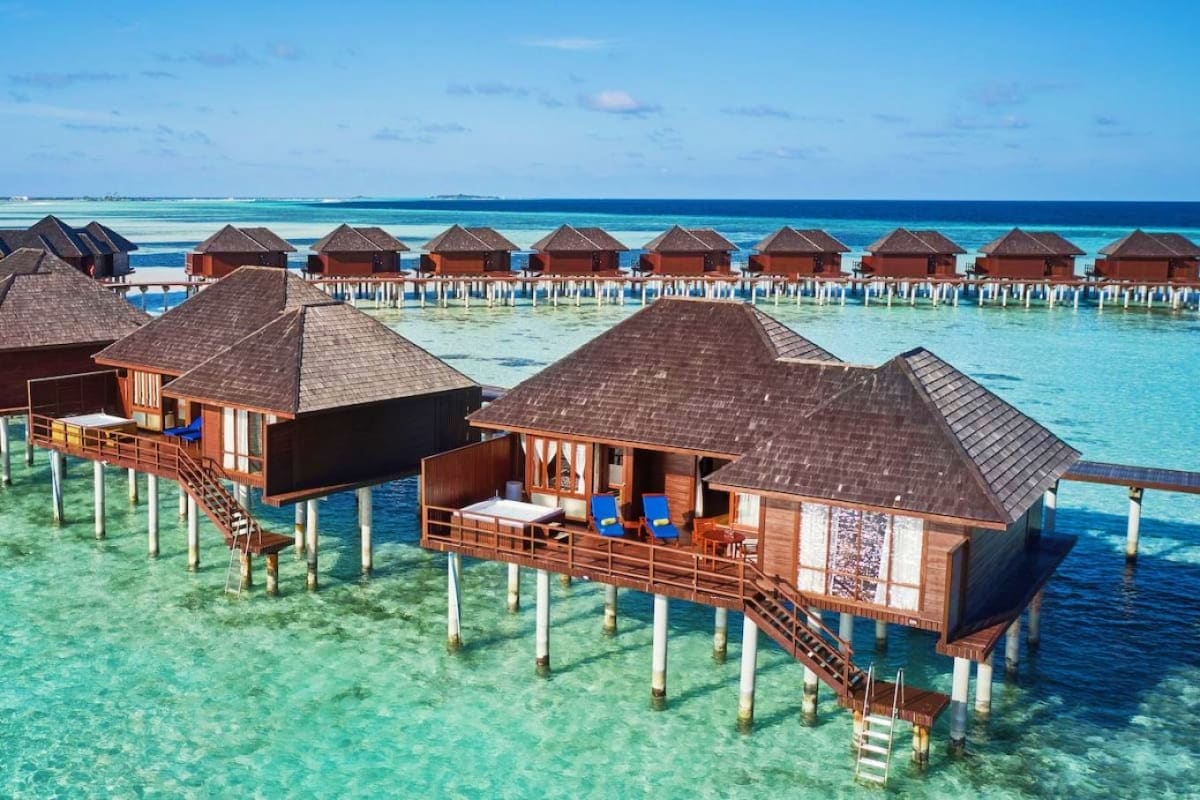 Overwater bungalows with thatched roofs at Sun Siyam Olhuveli Resort in the Maldives, surrounded by turquoise lagoon waters a