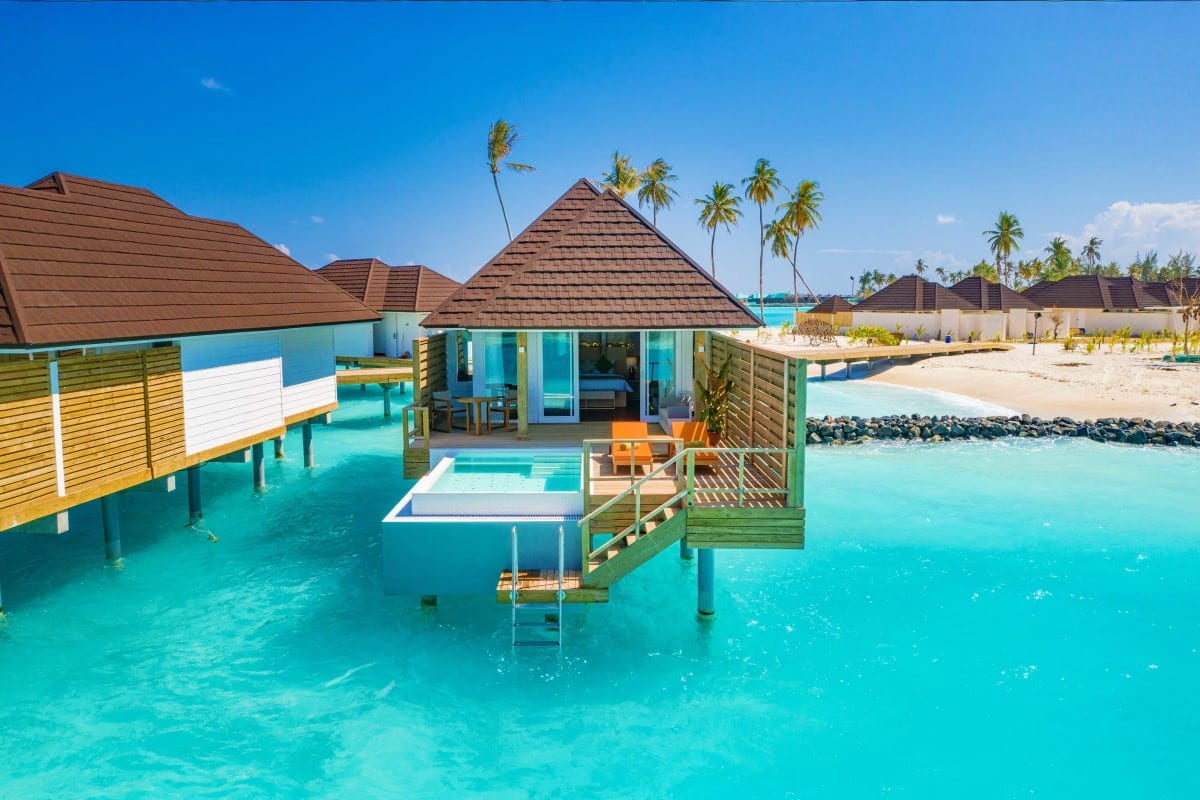 Luxury overwater bungalows with thatched roofs at Sun Siyam Olhuveli Resort in the Maldives, featuring turquoise lagoon water