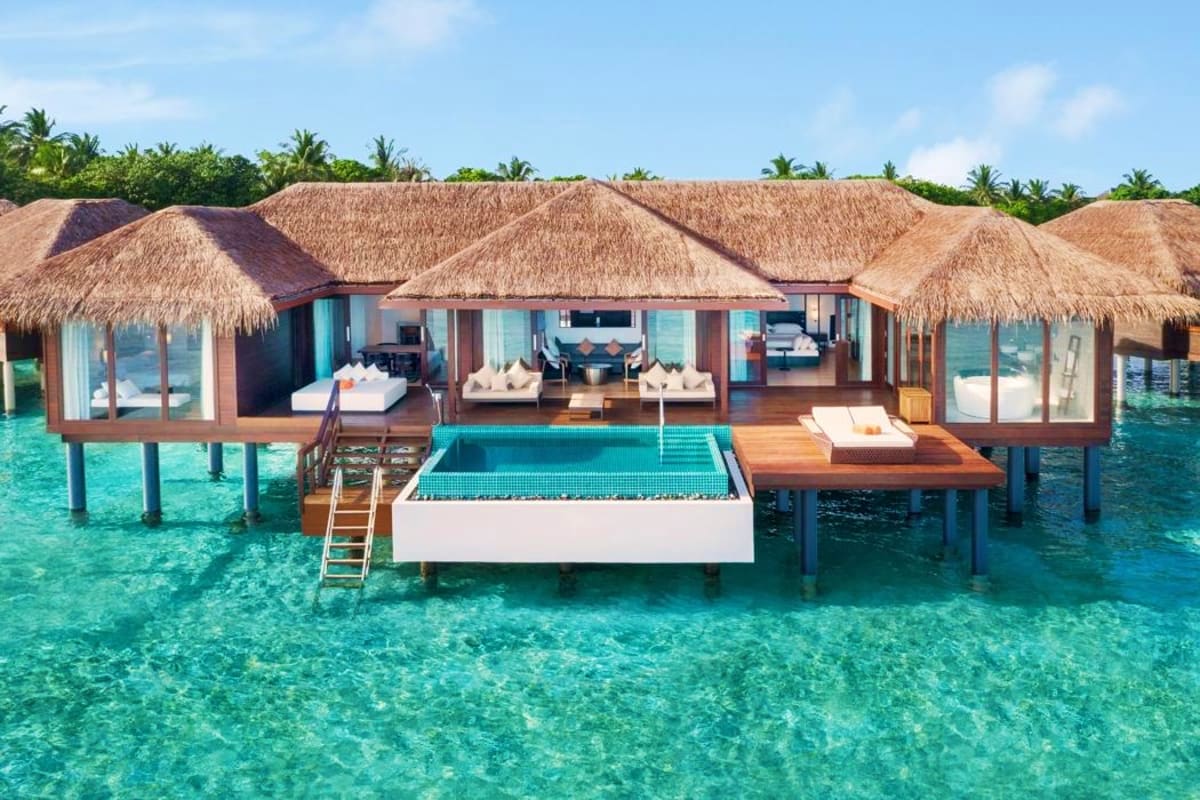 Luxury overwater bungalows with thatched roofs and private pools at a tropical Maldives resort in clear turquoise waters.