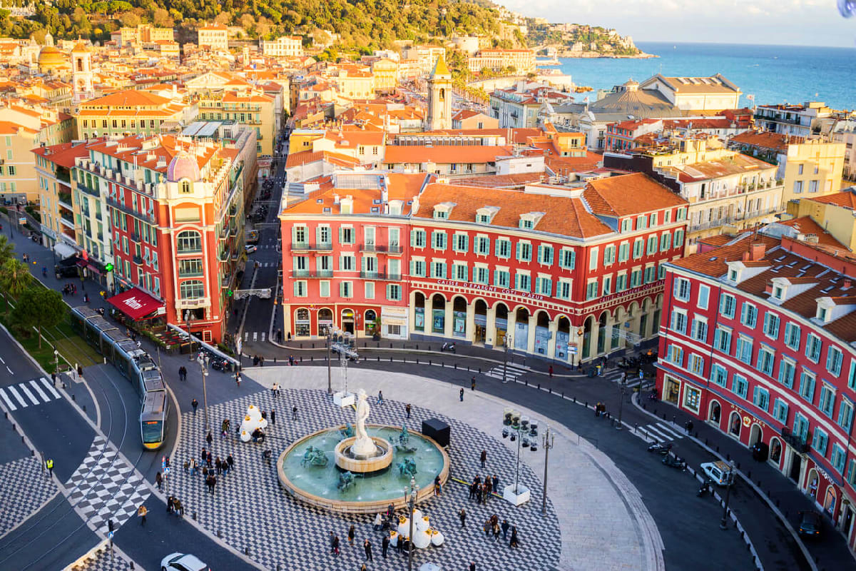 Swiss French Highlights with French Riviera Aerial view of Nice's Promenade des Anglais plaza with fountain, colorful Mediterranean buildings, and turquoise coastline