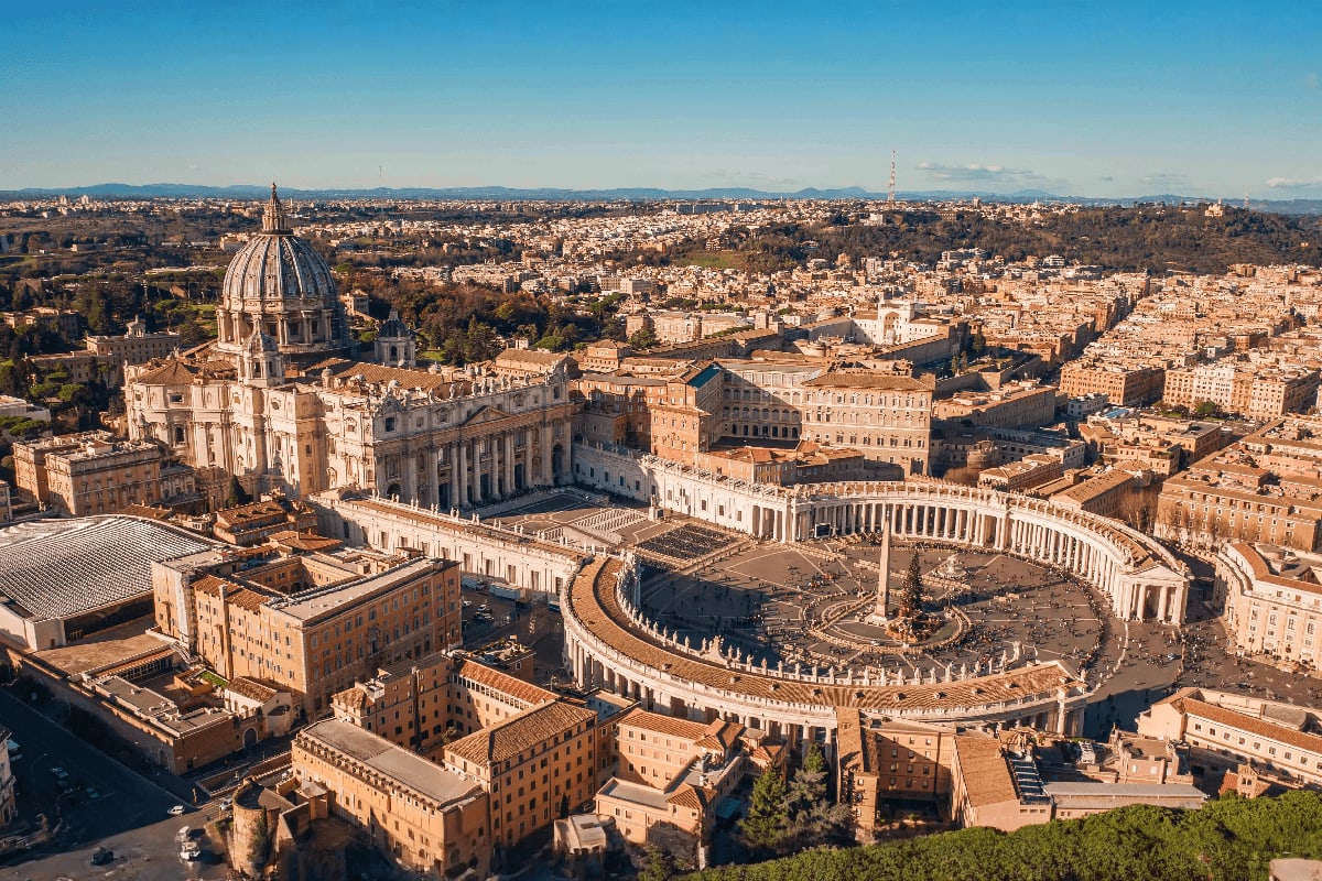 Aerial view of Vatican City with St. Peter's Basilica dome and colonnade square surrounded by Rome's terracotta buildings