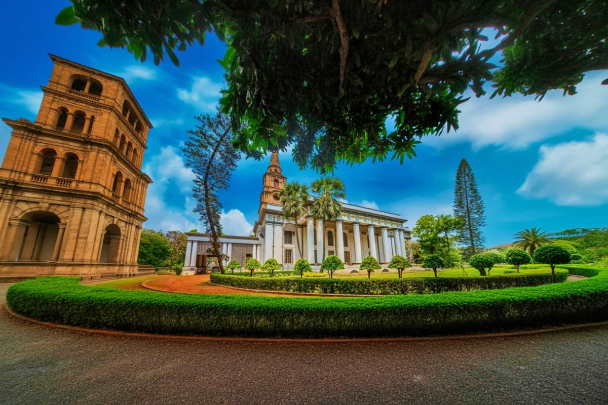Historic colonial church with bell tower and white neoclassical chapel surrounded by manicured gardens and tropical trees und