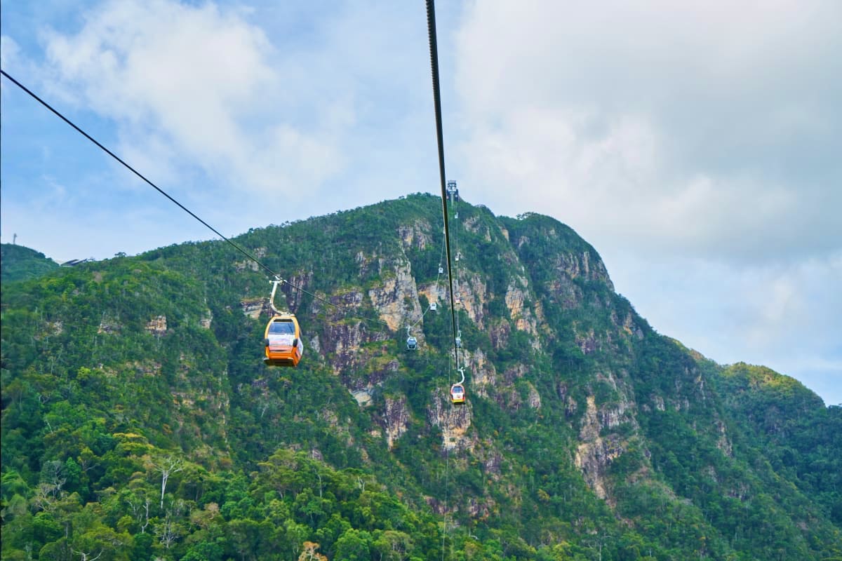 Best of Kazakhstan Cable car gondolas ascending a forested mountain cliff in Kazakhstan with rocky peaks in background