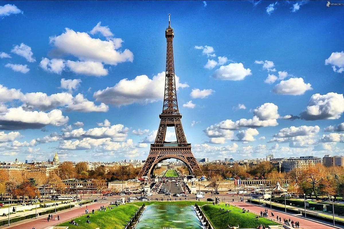 Eiffel Tower in Paris with Trocadéro Gardens, reflecting pool, and blue sky with white clouds on a clear day