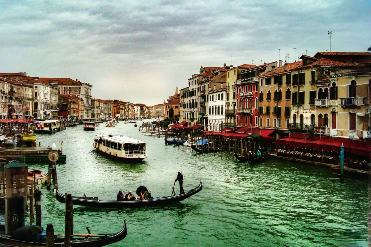 Italy and Switzerland Gondolas and boats on the Grand Canal in Venice with colorful historic buildings lining the waterway under a cloudy sky