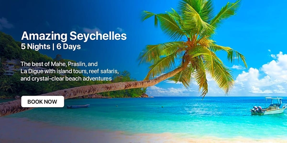 Tropical beach in Seychelles with palm tree, turquoise water, fishing boats, and blue sky