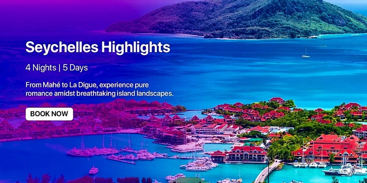 Aerial view of Seychelles islands with turquoise waters, red-roofed buildings, sailboats, and lush green vegetation under blu