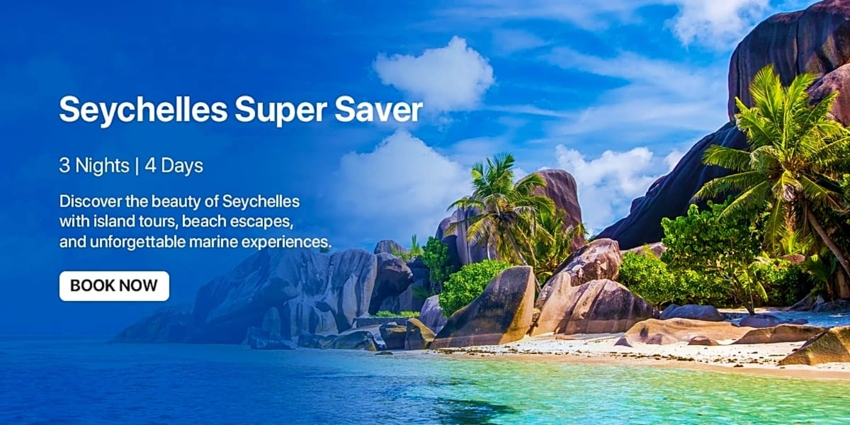 Tropical Seychelles beach with granite boulders, palm trees, turquoise water, and blue sky with white clouds