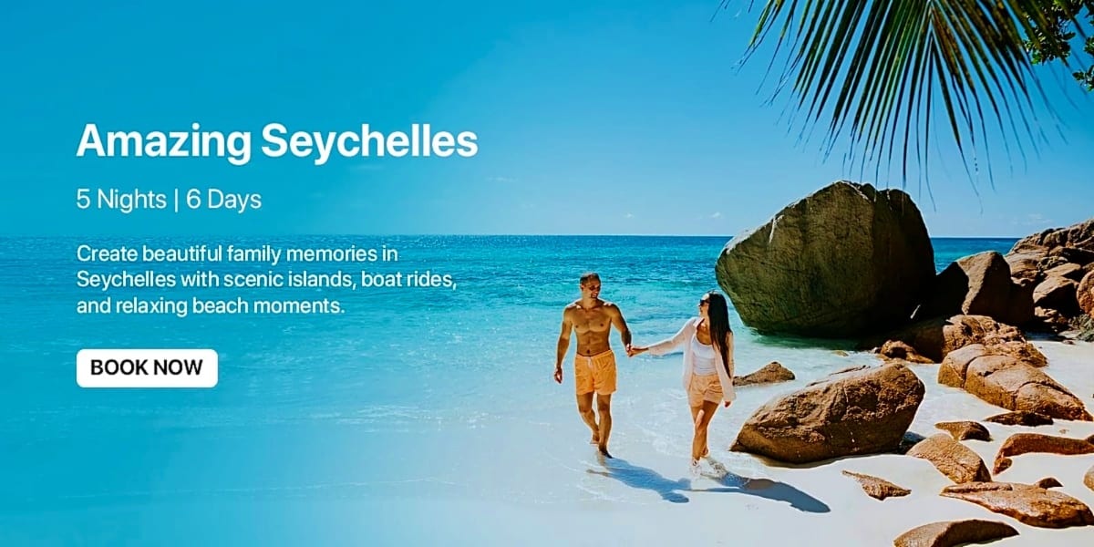 Couple walking in turquoise water on Seychelles beach with large granite boulders and palm tree fronds overhead