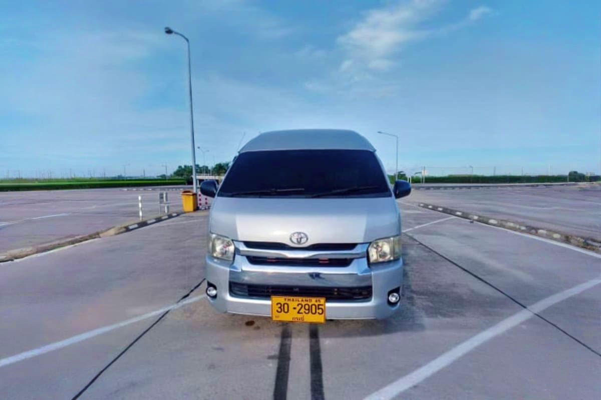 White Toyota van with yellow Thailand license plate parked on empty highway, used for Hua Hin to Bangkok hotel transfers