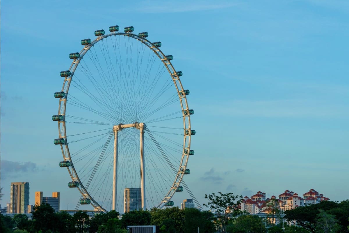 Asiatique Sky Ferris Wheel in Bangkok Singapore Flyer observation wheel against blue sky with city buildings and residential structures visible in background