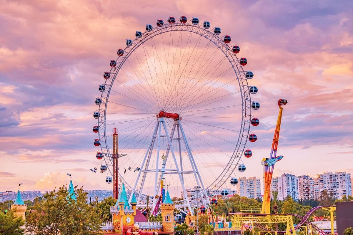 Asiatique Sky Ferris Wheel in Bangkok The London Eye ferris wheel at sunset with colorful amusement park rides and buildings in the background under a purple and p