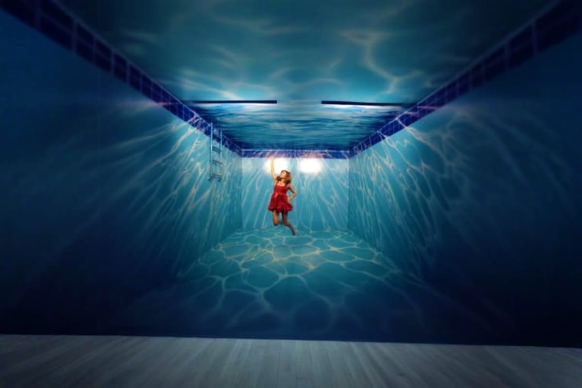 Art in Paradise Girl in red dress standing in underwater tunnel viewing a lit opening above, creative 3D art installation