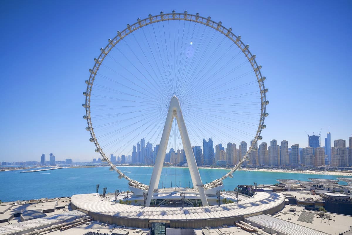 Ain Dubai observation wheel with white central pillar and cable supports overlooking Dubai coastline and turquoise water