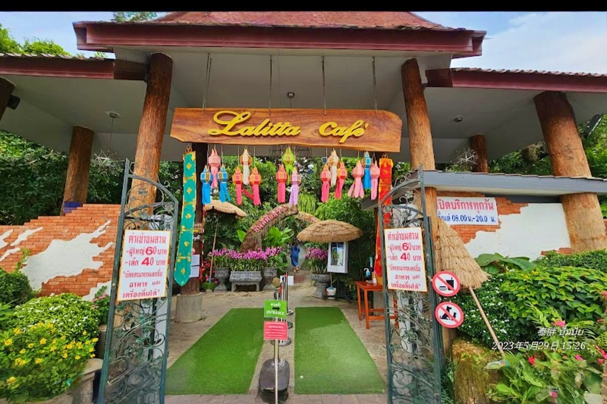 Entrance to Lalitta Cafe with traditional Thai architecture, wooden pillars, colorful hanging lanterns, and decorative gates