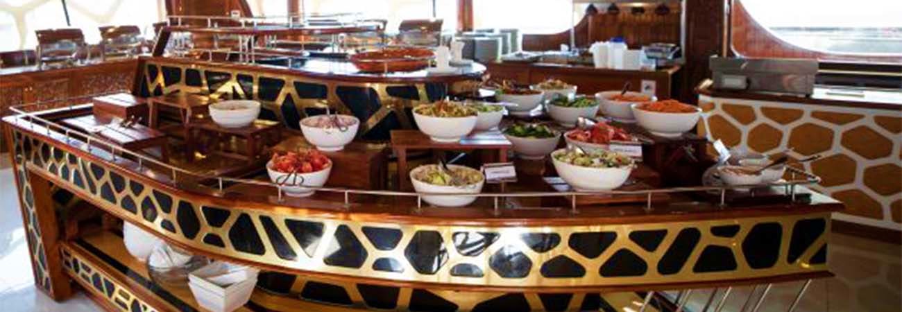 Elegant buffet spread with multiple dishes in white bowls on a curved dining counter with giraffe-print design on Ocean Empre