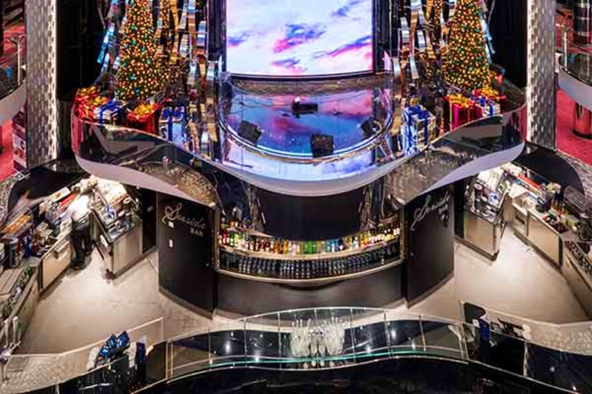 Overhead view of MSC Seaview's atrium with large curved LED screen displaying sunset sky, decorated with golden garland and g