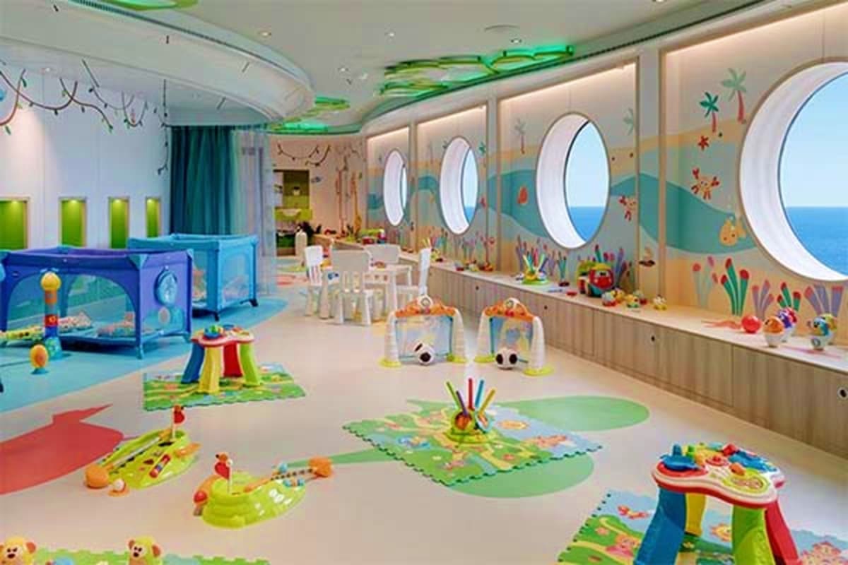 Modern colorful children's daycare room with porthole windows, play mats, toys, and interactive activity stations aboard MSC 