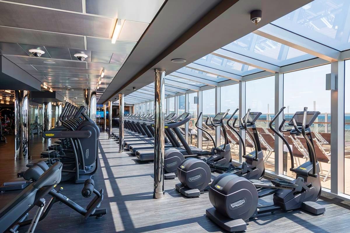 Modern gym with cardio equipment and floor-to-ceiling windows overlooking cityscape on MSC Seaview cruise ship