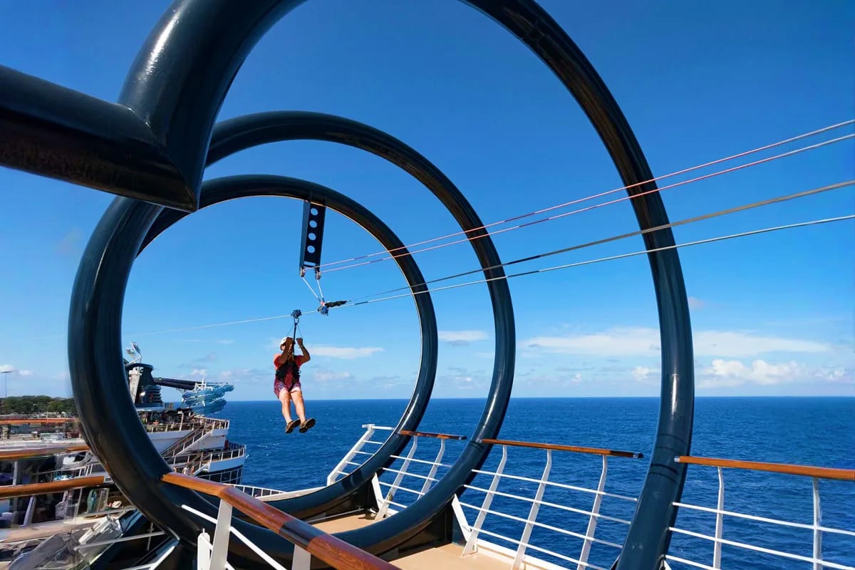 Person zip-lining through circular rings on MSC Seaview cruise ship deck over ocean