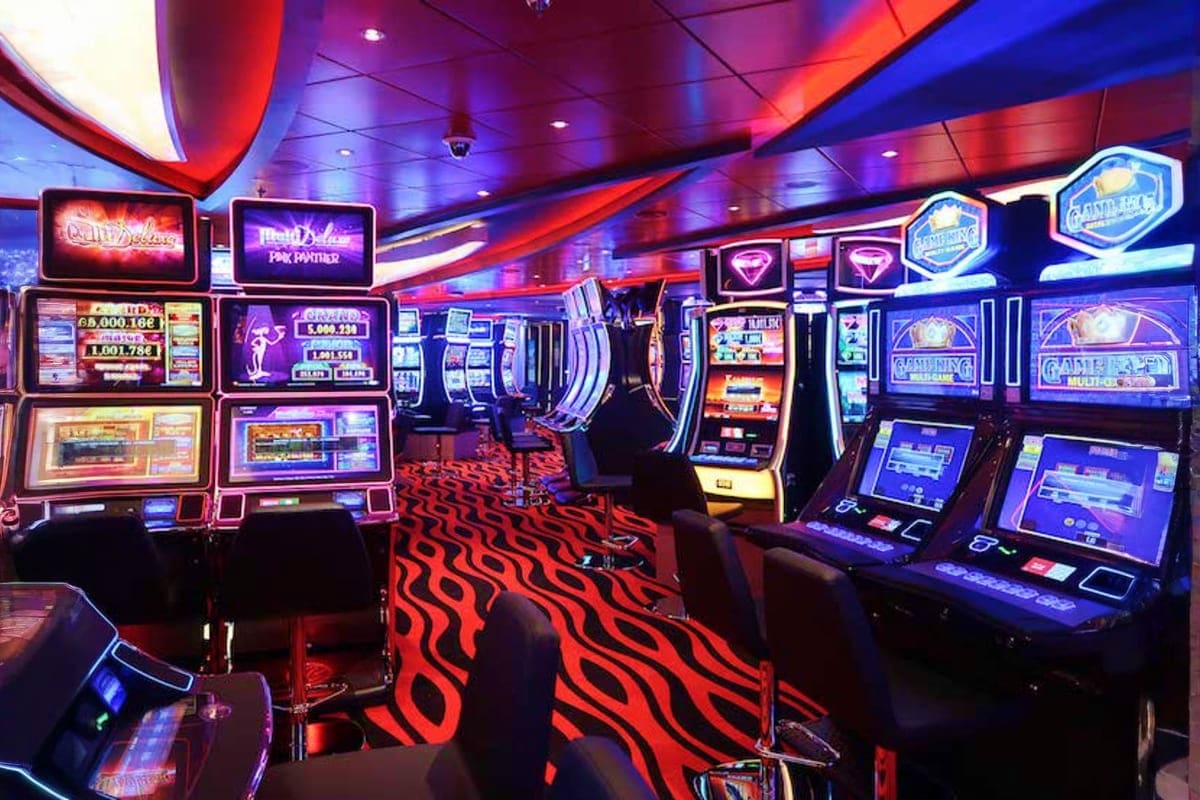 Modern casino floor on MSC Seaview with slot machines, neon signage, red and blue ambient lighting, and patterned carpet