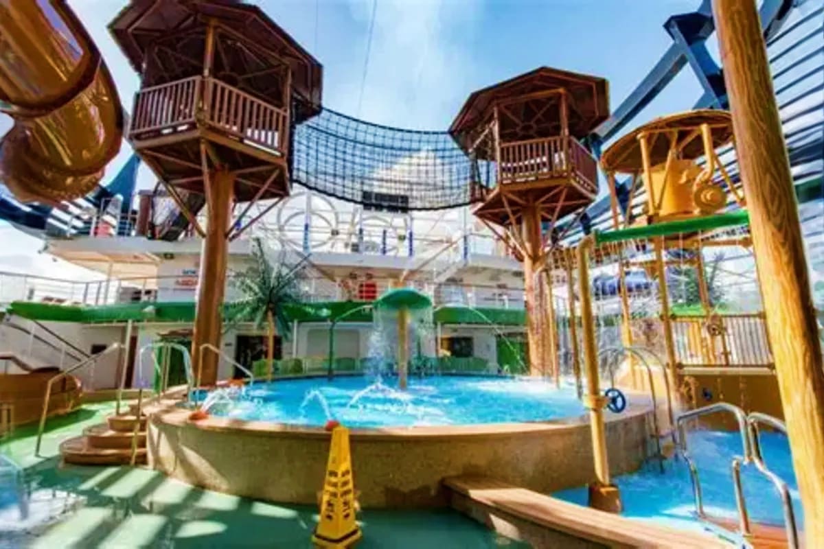 Indoor water park area on MSC Seaview with wooden tree house structures, blue pools, water slides, and tropical-themed deck f