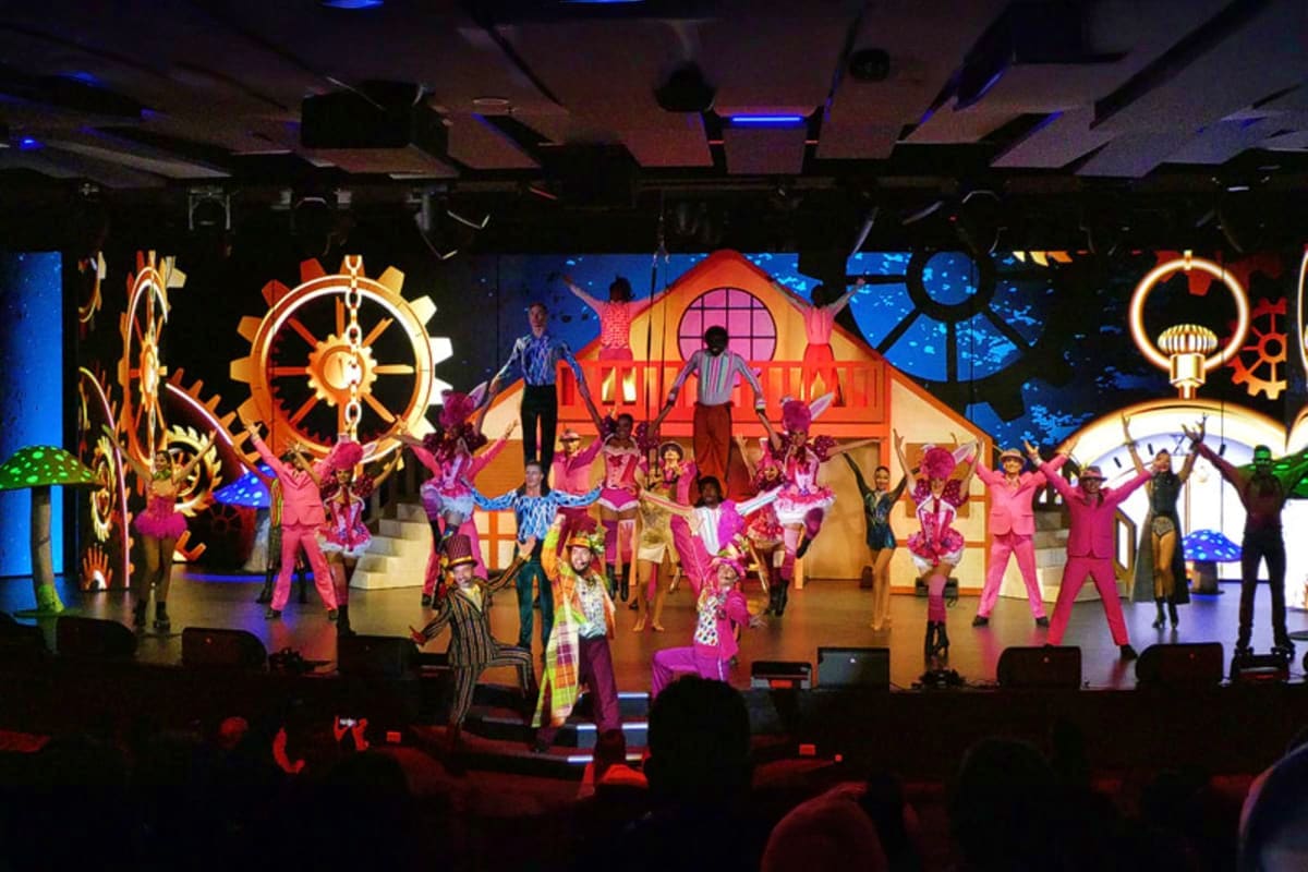 Colorful theatrical stage show on MSC Seaview cruise ship with performers in pink costumes dancing among illuminated nautical
