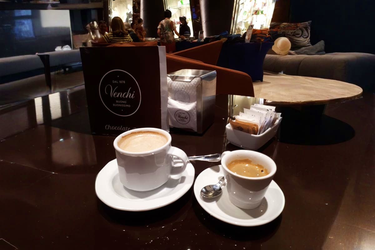 Two cappuccinos and an espresso at Venchi café with customers in background on MSC Seaview cruise ship