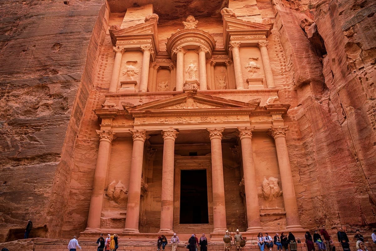 Jordan Amman Classic Tour Package The Treasury facade at Petra, Jordan, carved into rose-colored sandstone with ornate columns and carved details, with tourist