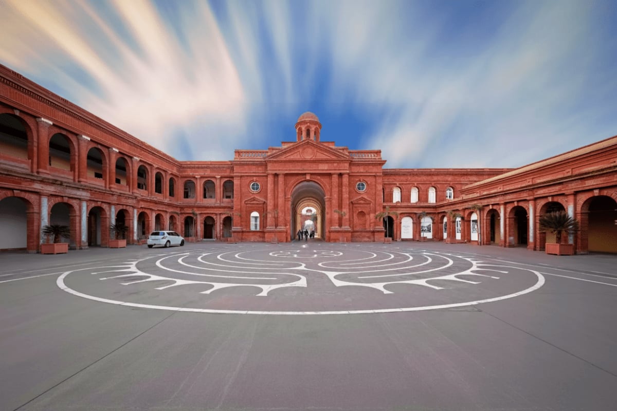 Amritsar Highlights Tour with Temples History and Border Retreat Red brick courtyard with white spiral mandala pattern and historic colonial architecture building in Amritsar, India