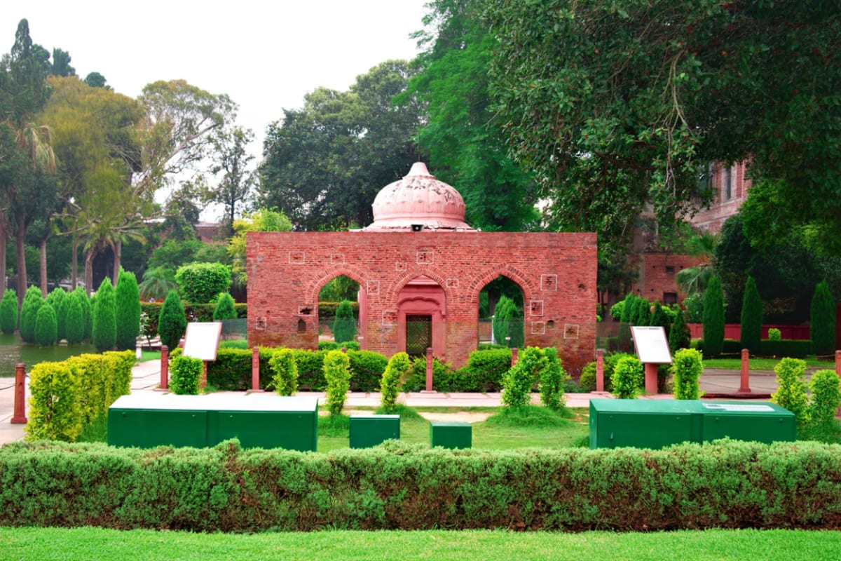 Amritsar Highlights Tour with Temples History and Border Retreat Red brick historic structure with pink dome surrounded by manicured gardens and cypress trees in Amritsar, India