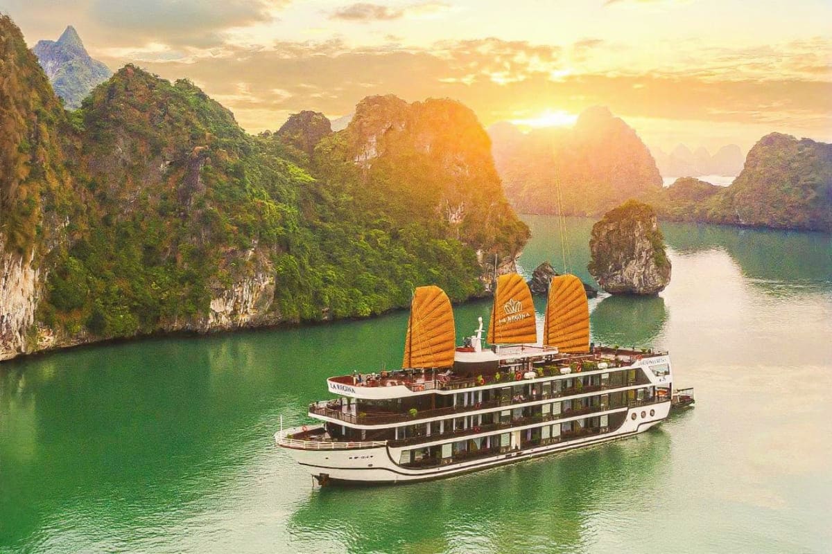 Halong Waves and Phu Quoc Days Luxury cruise ship with golden sails sailing through Halong Bay limestone karsts at sunset in Vietnam