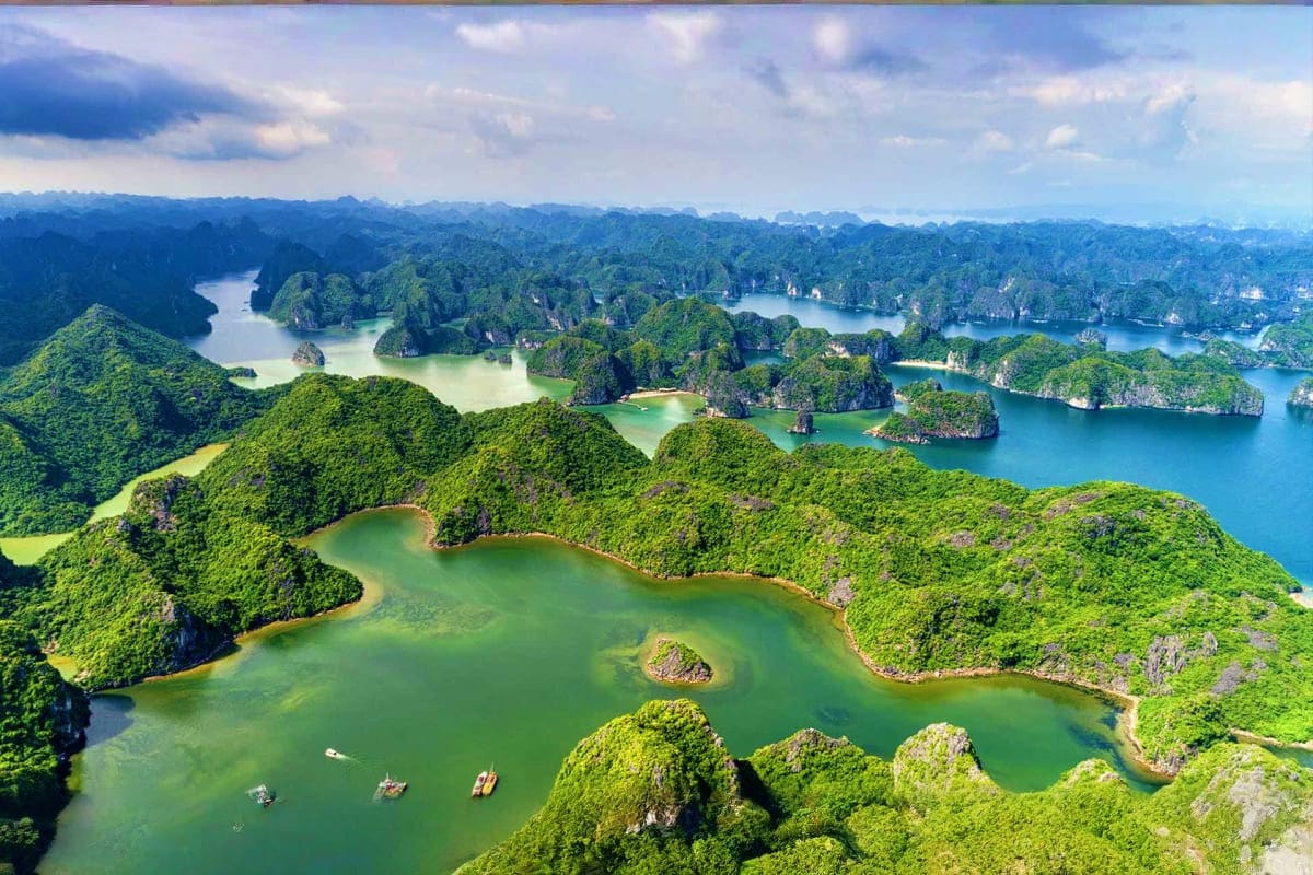 Aerial view of Halong Bay limestone karsts and emerald waters with traditional fishing boats and lush tropical vegetation