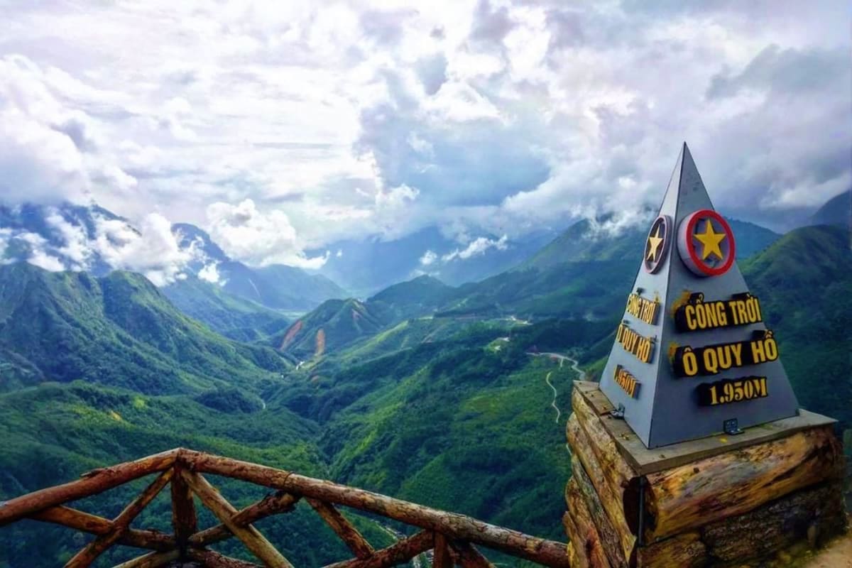 Vietnam Scenic Adventure for Friends O Quy Ho mountain pass marker at 1,950m elevation overlooking lush green valleys and mountains with wooden railing in foregro
