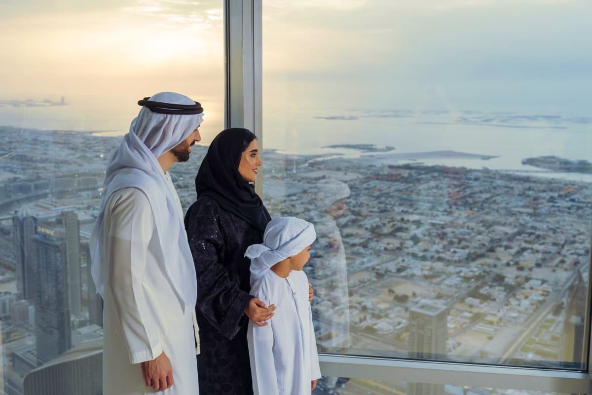 Arab family viewing cityscape from Burj Khalifa observation deck with panoramic windows overlooking Dubai