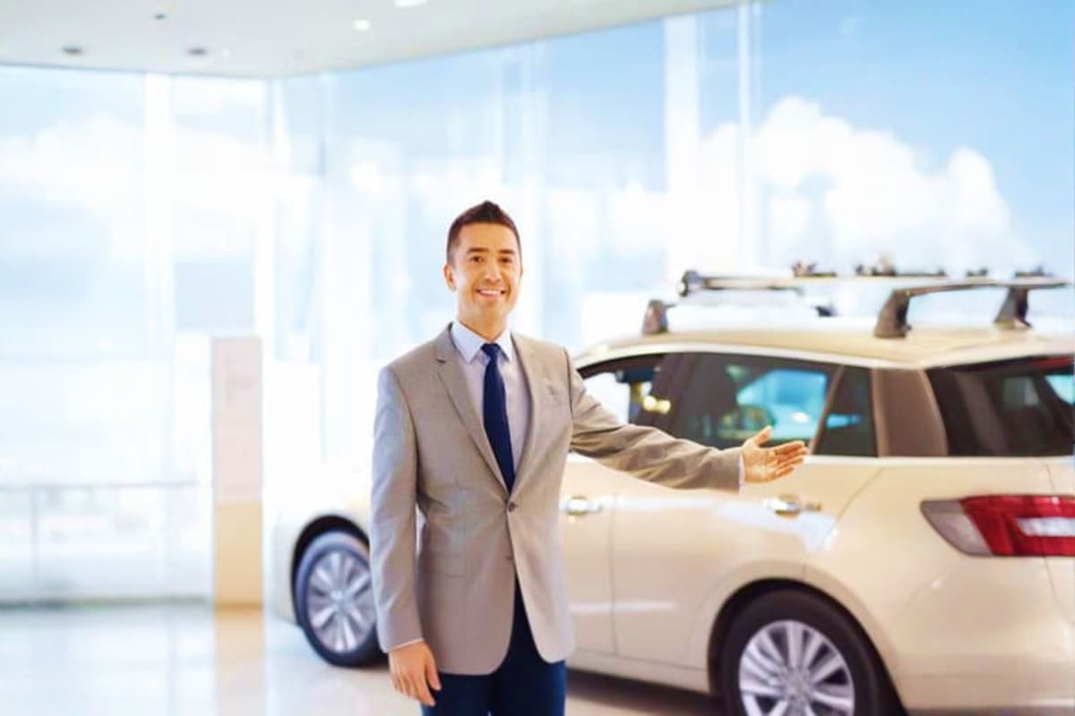 Private Half Day Sightseeing Tour Dubai Car salesman in business attire presenting white SUV in modern showroom with city skyline view