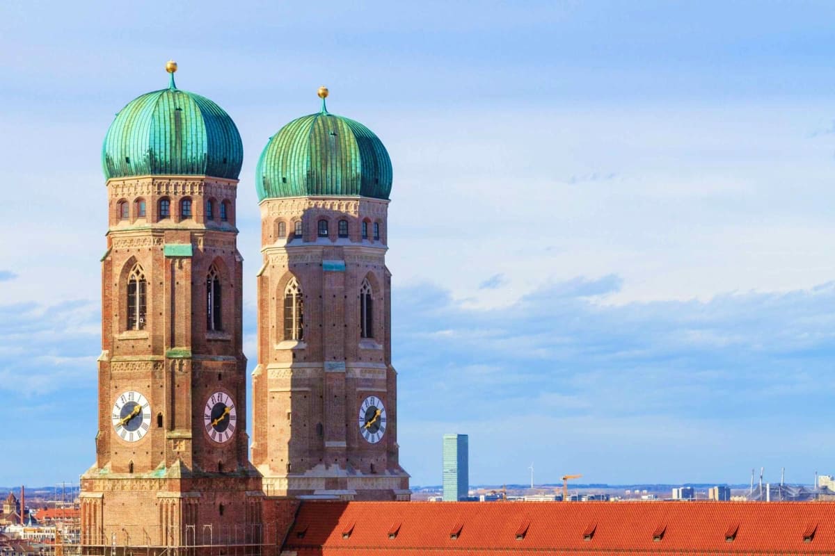 Discover Munich Old Town Guided Walking Tour Twin brick towers with green copper domes and clocks on Munich's Frauenkirche church overlooking the city skyline