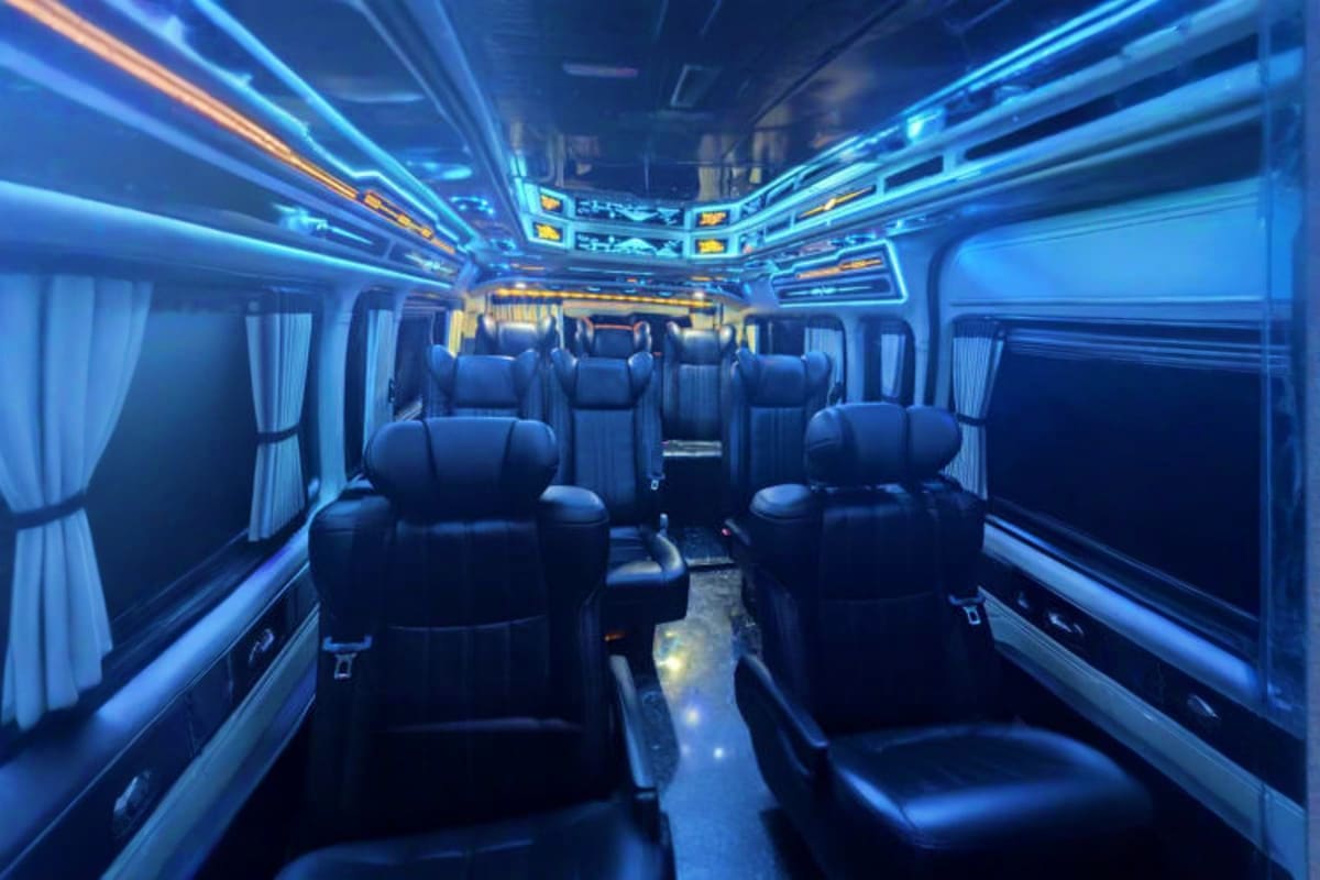Ho Chi Minh Airport Drop off Interior of luxury charter bus with black leather seats, blue ambient lighting, and white curtains for airport transfer servi