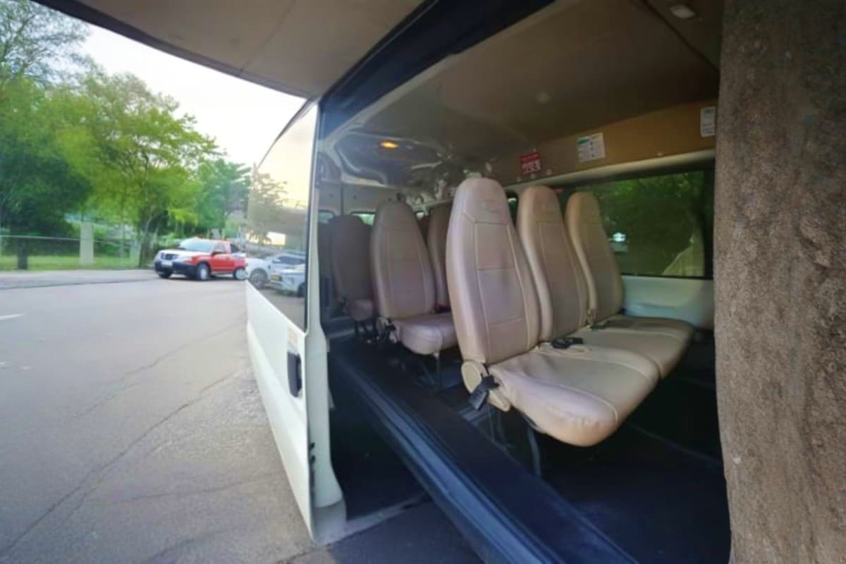 Ho Chi Minh Midnight Airport Pickup Interior view of white van with gray fabric seats, open sliding door showing passenger seating capacity for airport transfer