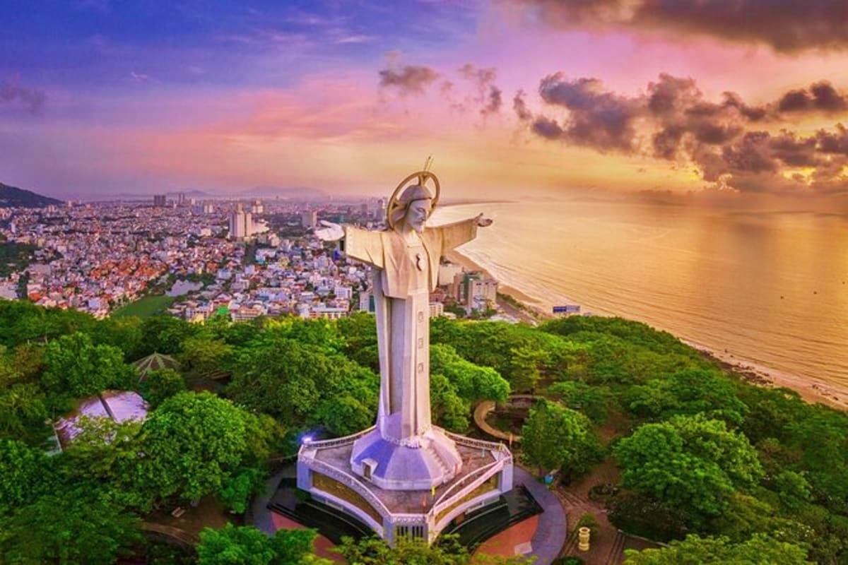 Vung Tau Day Trip Christ of Vung Tau statue overlooking coastal city and beach at sunset with arms outstretched