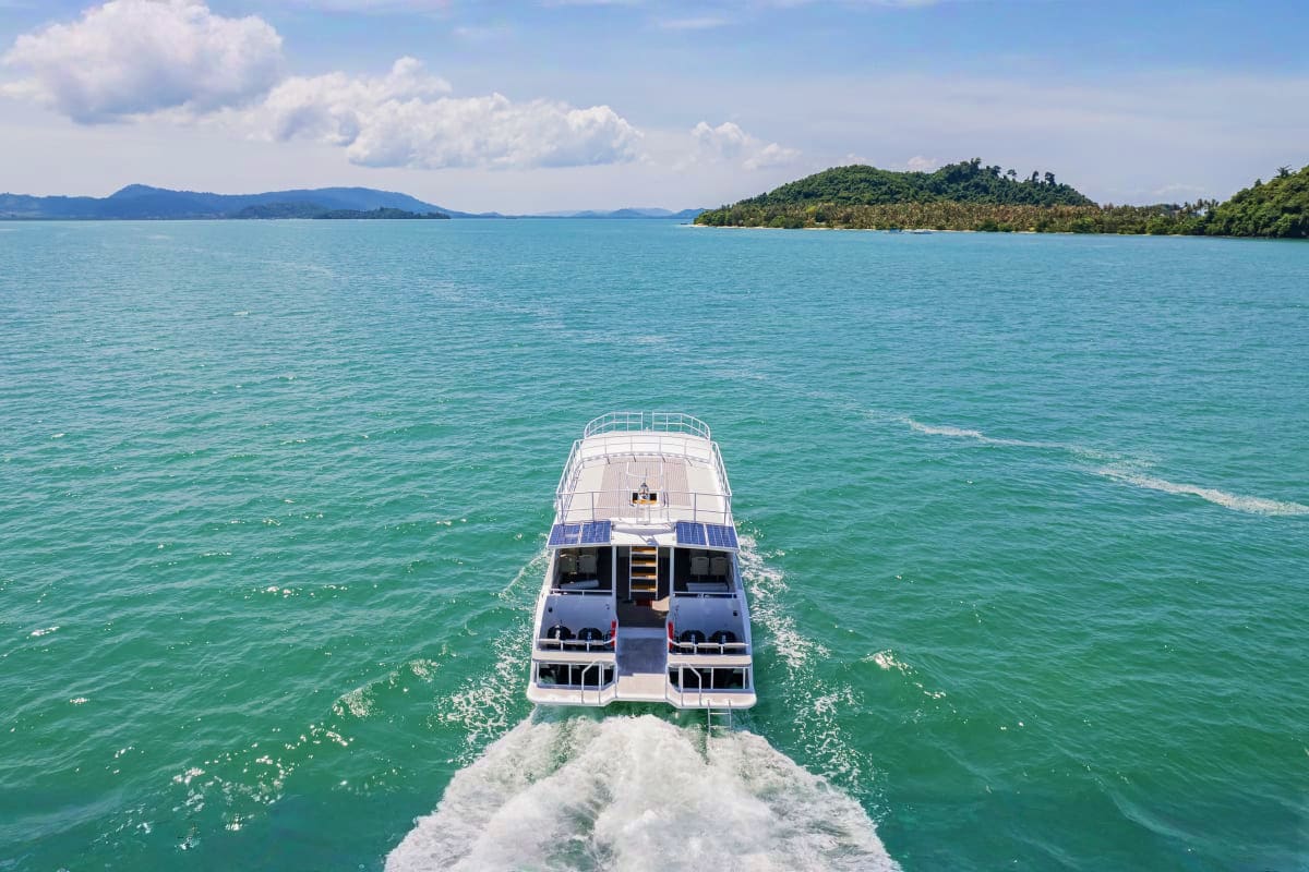 Speedboat traveling toward forested islands in turquoise water during Phi Phi Islands and Khai Island day trip