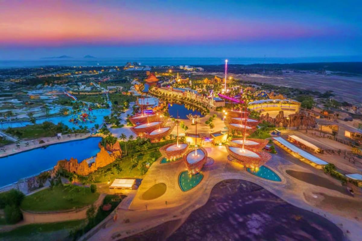 Aerial view of Vinwonders Nam Hoi An theme park at dusk with illuminated attractions, water features, and colorful structures