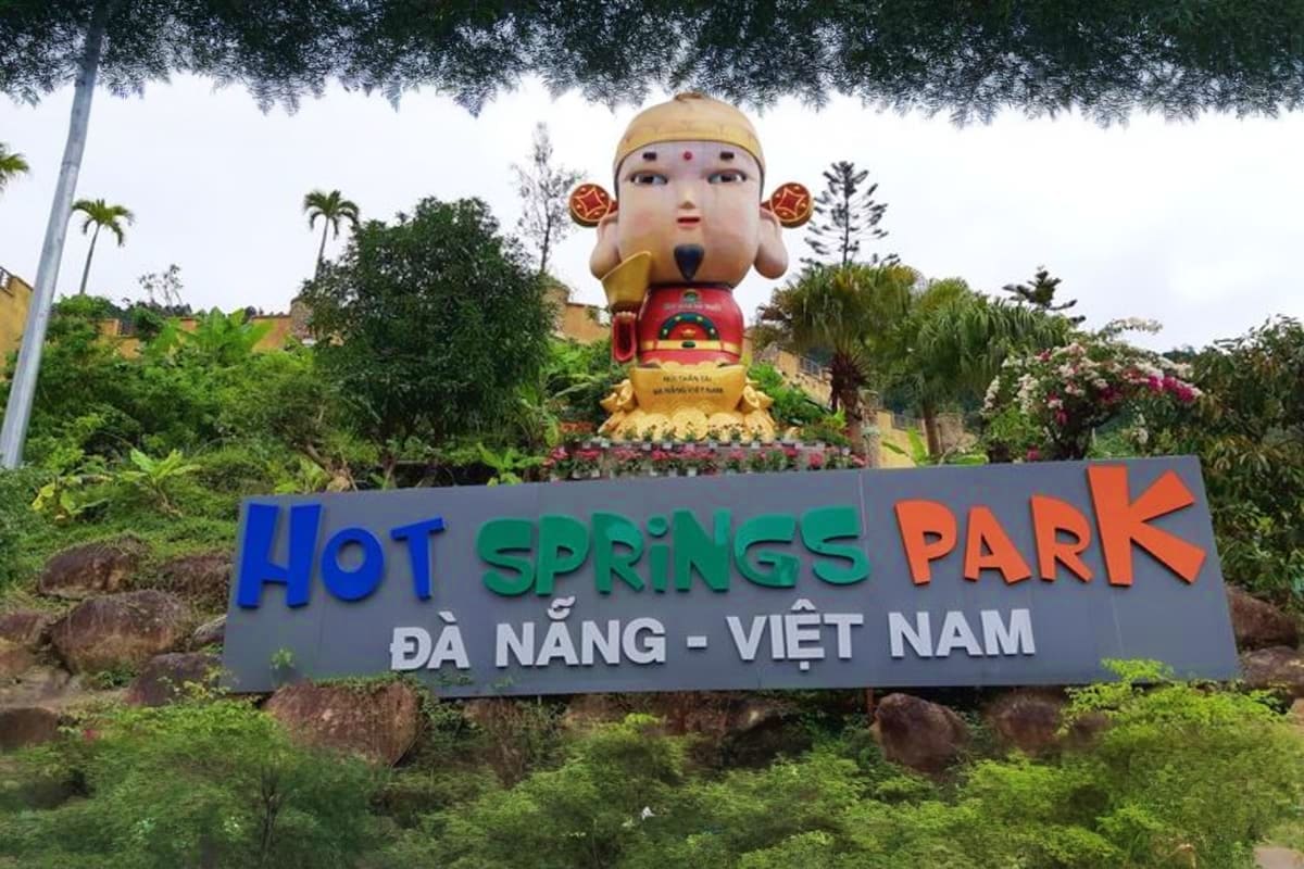 Hot Springs Park entrance sign in Da Nang Vietnam with large golden Buddha statue and colorful sign displaying park name