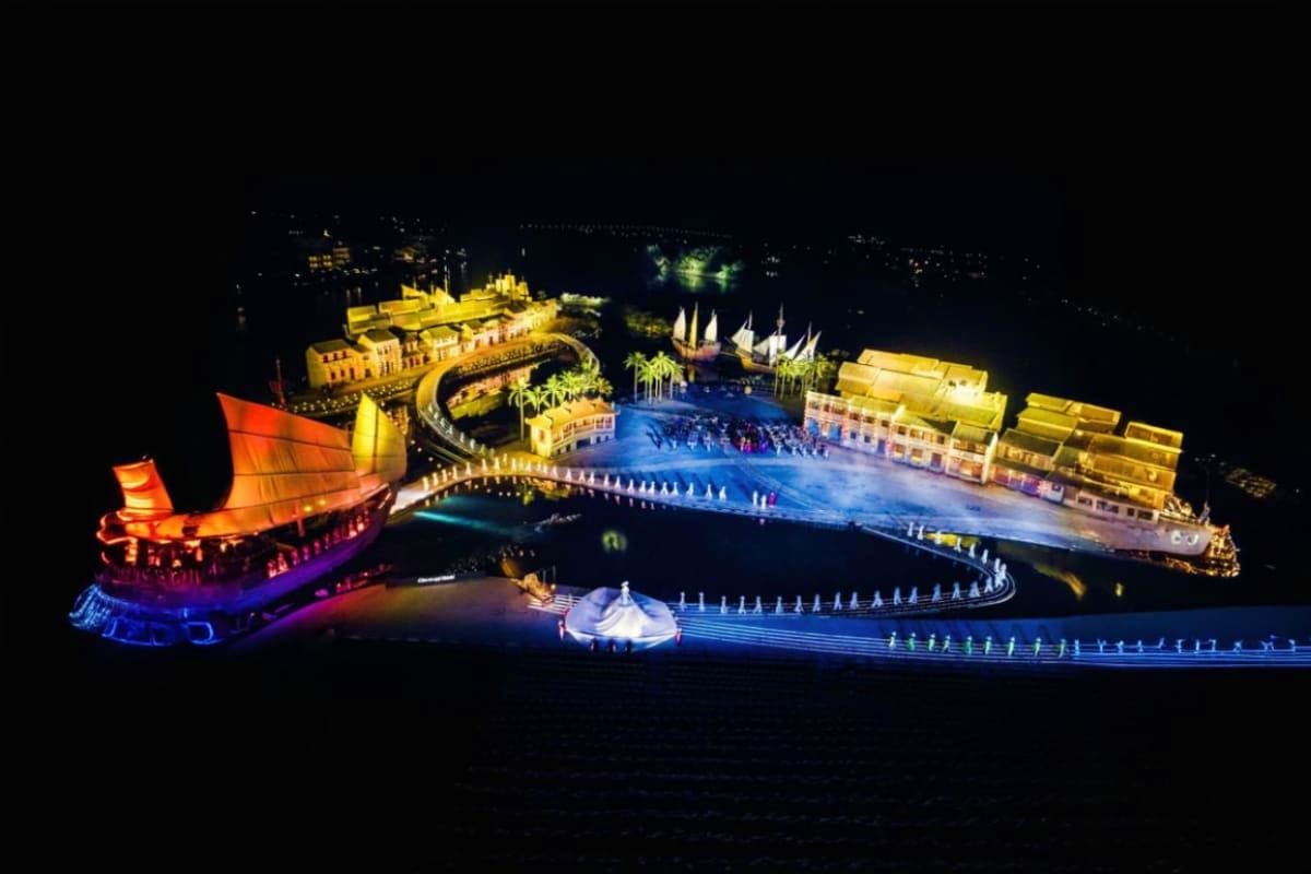 Nighttime aerial view of illuminated Hoi An Impression Theme Park featuring traditional Vietnamese architecture, glowing gold